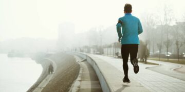 Runner exercising and jogging outdoor in fog and misty weather to stay active