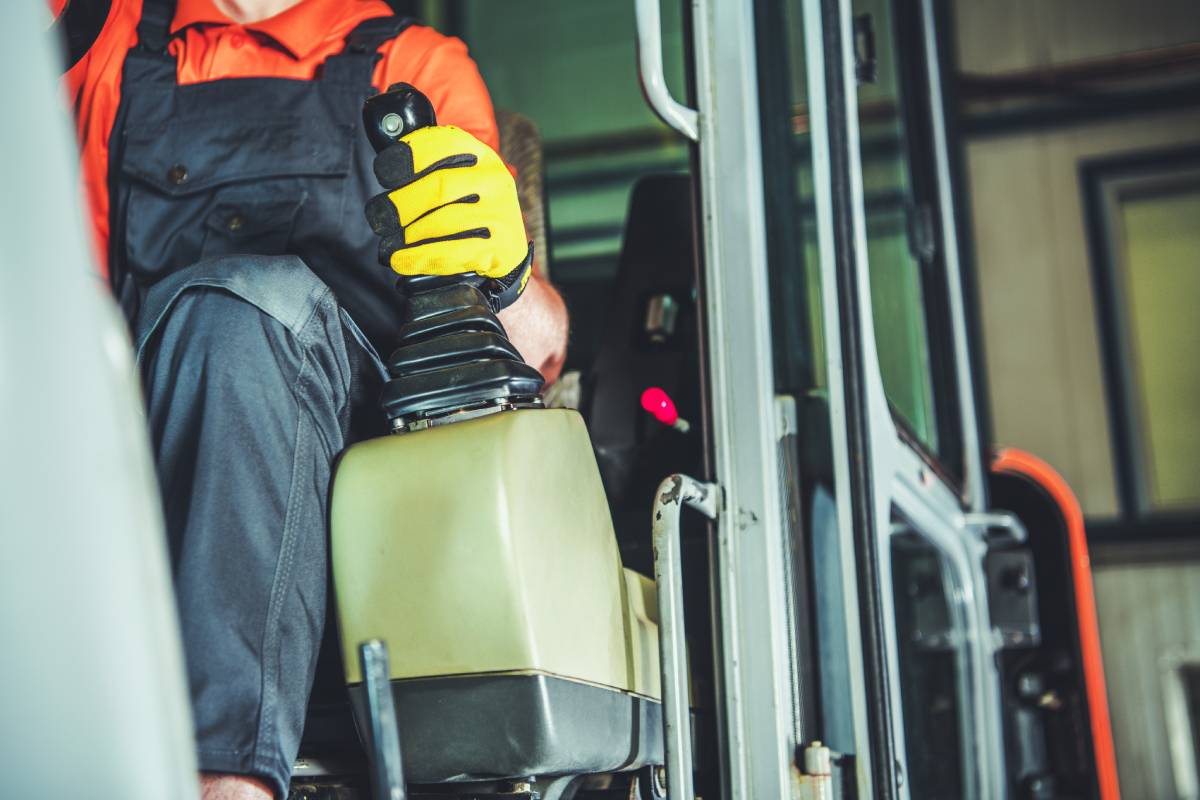 Heavy Duty Equipment Operator Holding His Hand on Manual Gear Shifter While Driving Out of the Garage. Industrial Machinery Theme.