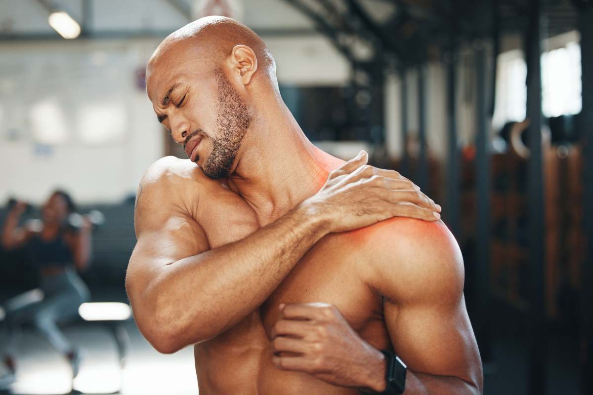 Shot of a muscular young man holding his shoulder in pain while exercising in a gym.