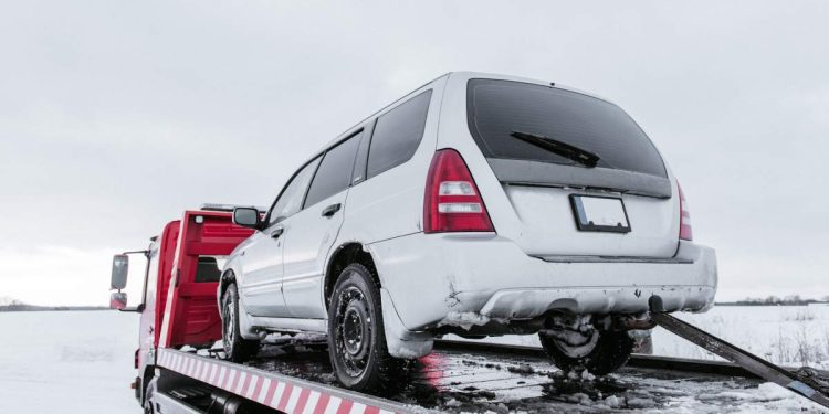 Car on tow truck on snow road