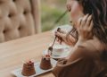 Crop photo of woman eating double tiramisu dessert decorated with fresh berries at the cafe