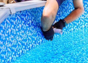 Maintenance worker installs water filtration system, chlorination system in frame swimming pool