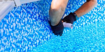 Maintenance worker installs water filtration system, chlorination system in frame swimming pool