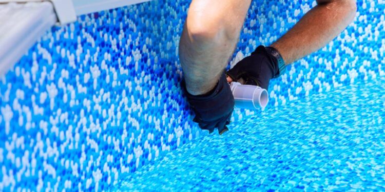 Maintenance worker installs water filtration system, chlorination system in frame swimming pool